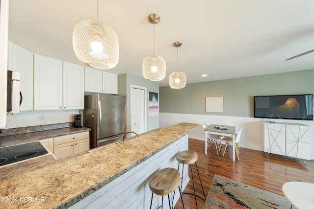 kitchen with white cabinetry, dark hardwood / wood-style floors, decorative light fixtures, and stainless steel refrigerator