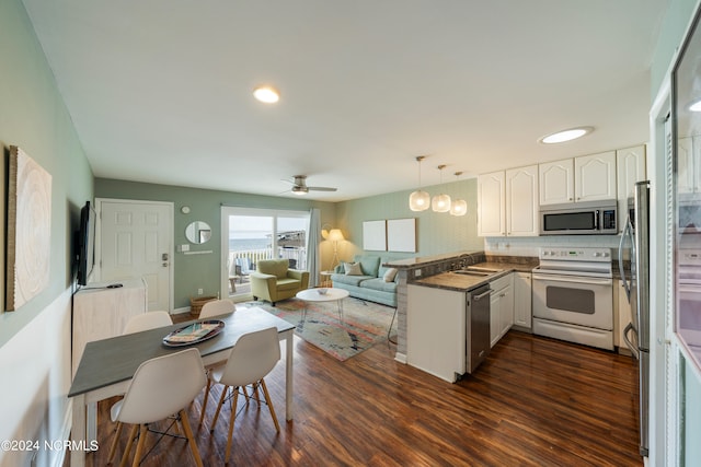 kitchen featuring stainless steel appliances, hanging light fixtures, white cabinets, dark wood-type flooring, and kitchen peninsula