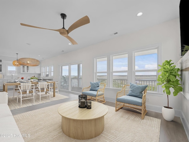 living room featuring light wood-style flooring, recessed lighting, visible vents, baseboards, and a ceiling fan