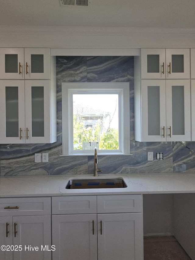 109 Old Village Ln, North Topsail Beach, NC 28460 - kitchen featuring a sink, crown molding, white cabinetry, glass insert cabinets, and backsplash