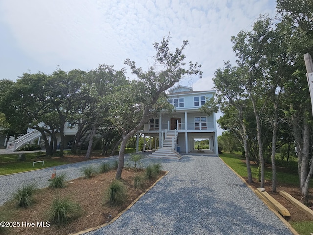 109 Old Village Ln, North Topsail Beach, NC 28460 - beach home featuring stairway, a carport, gravel driveway, and covered porch