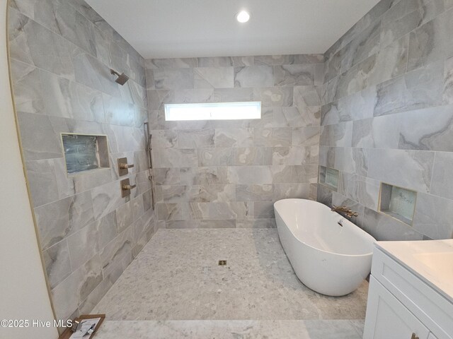 109 Old Village Ln, North Topsail Beach, NC 28460 - full bathroom featuring a soaking tub, tiled shower, vanity, and tile walls