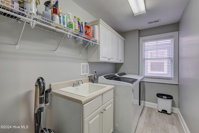 washroom featuring cabinets, washing machine and dryer, sink, and light wood-type flooring