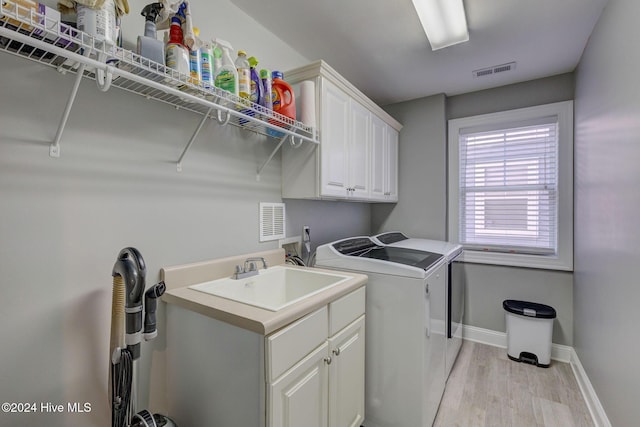 230 Third Ave Unit A, Kure Beach, NC 28449 - clothes washing area featuring washer and clothes dryer, light wood finished floors, cabinet space, and baseboards