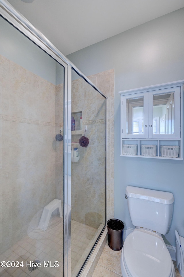 bathroom featuring toilet, an enclosed shower, and tile patterned floors