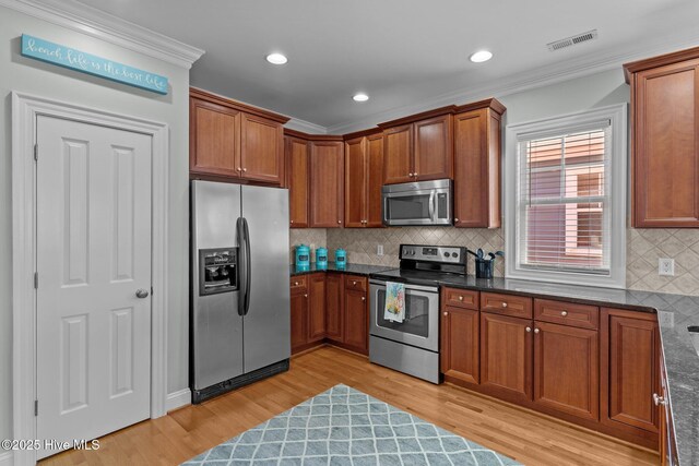 230 Third Ave Unit A, Kure Beach, NC 28449 - kitchen featuring stainless steel appliances, light wood-type flooring, crown molding, brown cabinetry, and tasteful backsplash