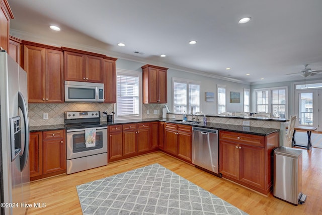 230 Third Ave Unit A, Kure Beach, NC 28449 - kitchen with appliances with stainless steel finishes, ornamental molding, a peninsula, decorative backsplash, and light wood-style floors