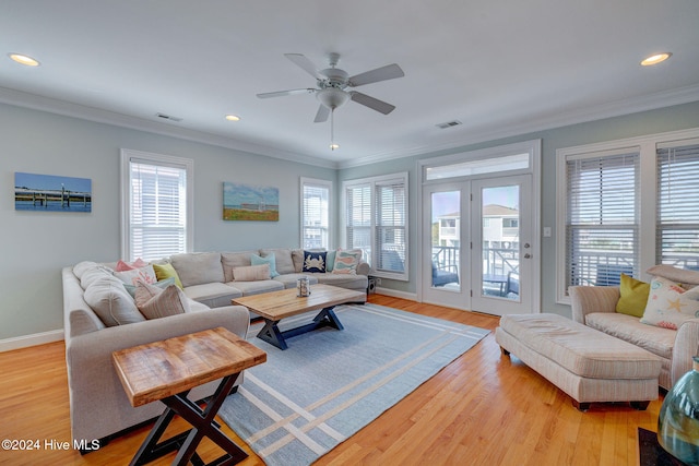 living room featuring ornamental molding, a wealth of natural light, and light hardwood / wood-style flooring