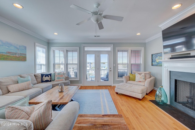 living room with light wood-type flooring, ceiling fan, and ornamental molding