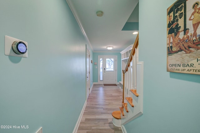 hallway with light hardwood / wood-style floors and crown molding