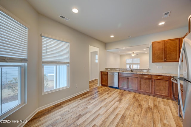 kitchen with light wood-type flooring, stainless steel appliances, plenty of natural light, and sink