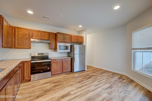 kitchen featuring decorative backsplash, stainless steel appliances, light stone counters, and light hardwood / wood-style floors