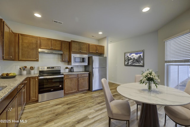 kitchen featuring a healthy amount of sunlight, light hardwood / wood-style floors, stainless steel appliances, and tasteful backsplash