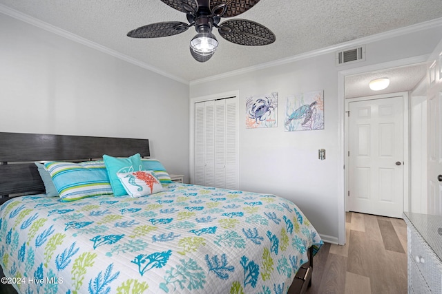 bedroom with ceiling fan, a textured ceiling, light hardwood / wood-style flooring, crown molding, and a closet