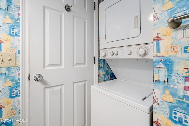 clothes washing area featuring stacked washer and clothes dryer