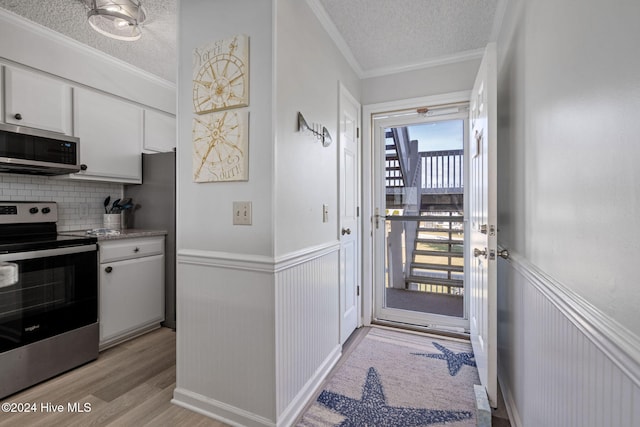 kitchen featuring white cabinets, light hardwood / wood-style floors, backsplash, and appliances with stainless steel finishes