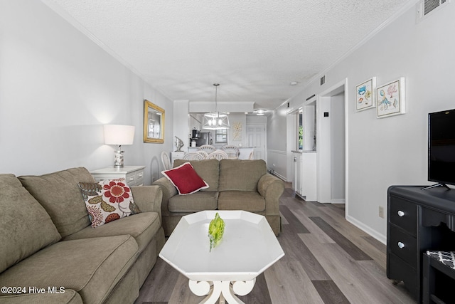 living room with hardwood / wood-style flooring, a textured ceiling, and ornamental molding