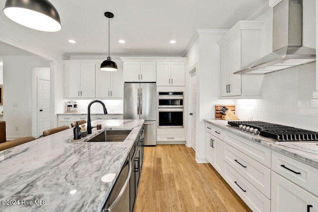 kitchen featuring light stone countertops, white cabinets, stainless steel appliances, and wall chimney range hood