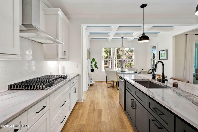 kitchen with wall chimney exhaust hood, sink, light hardwood / wood-style flooring, white cabinetry, and hanging light fixtures