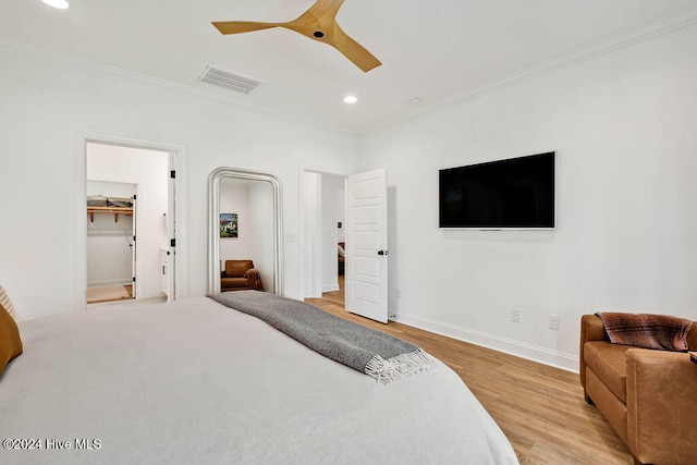 bedroom with light hardwood / wood-style floors, a spacious closet, ceiling fan, and crown molding