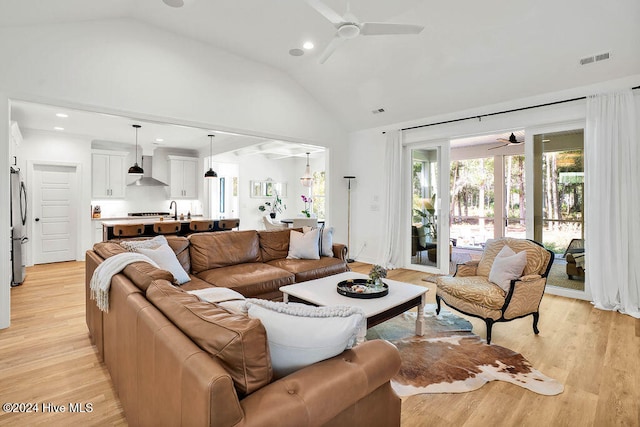 living room featuring light hardwood / wood-style floors, high vaulted ceiling, ceiling fan, and sink