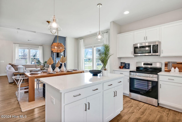 kitchen featuring white cabinets, appliances with stainless steel finishes, light hardwood / wood-style floors, and decorative light fixtures