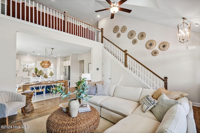 living room with high vaulted ceiling, wood-type flooring, and ceiling fan with notable chandelier