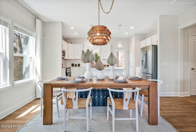 kitchen with white cabinets, stainless steel appliances, light hardwood / wood-style flooring, and decorative light fixtures