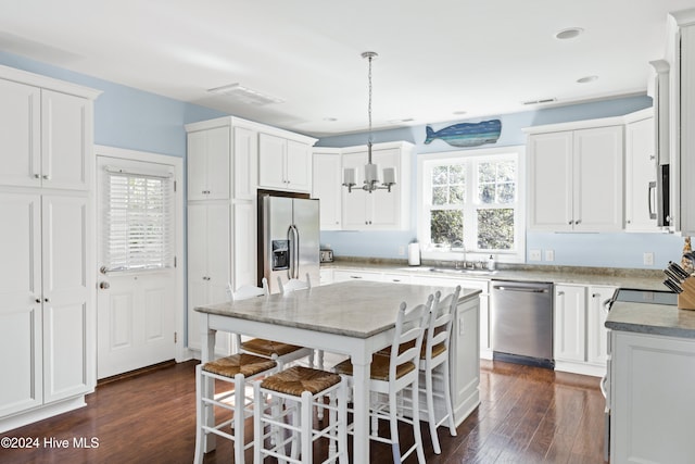 kitchen featuring stainless steel appliances, dark hardwood / wood-style floors, a kitchen island, white cabinetry, and decorative light fixtures