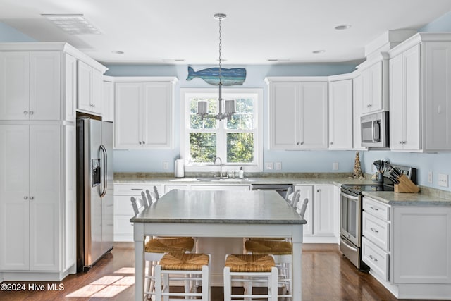 kitchen with pendant lighting, stainless steel appliances, white cabinets, and dark hardwood / wood-style flooring