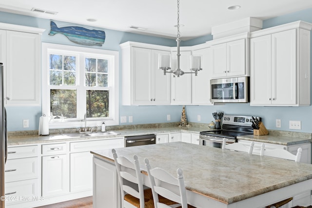 kitchen with stainless steel appliances, a breakfast bar area, sink, and decorative light fixtures