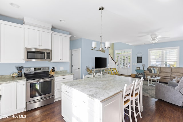 kitchen with dark hardwood / wood-style flooring, white cabinetry, appliances with stainless steel finishes, and a center island