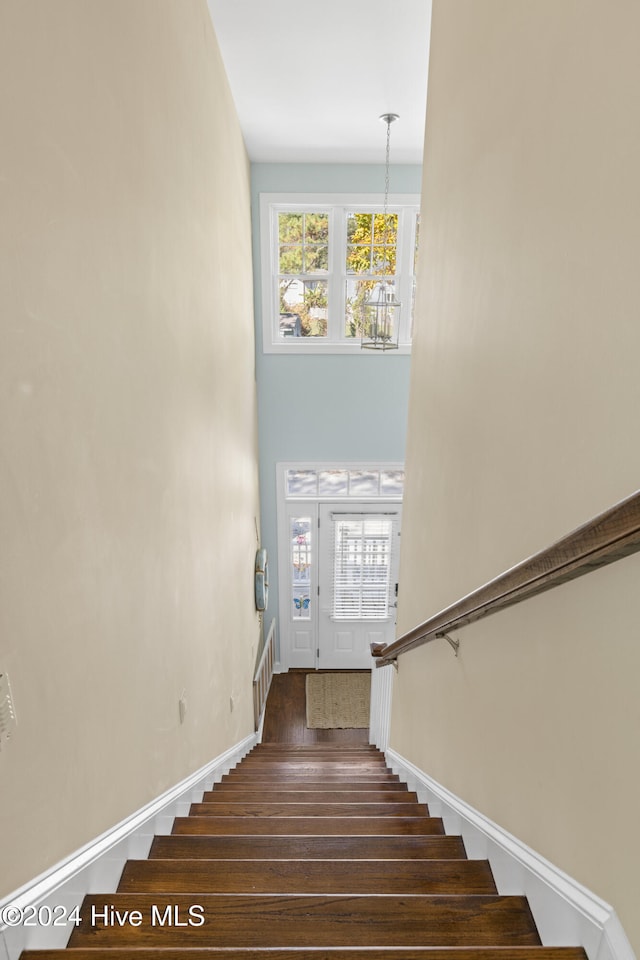 staircase featuring hardwood / wood-style flooring and an inviting chandelier