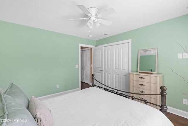 bedroom featuring dark hardwood / wood-style flooring, ceiling fan, and a closet