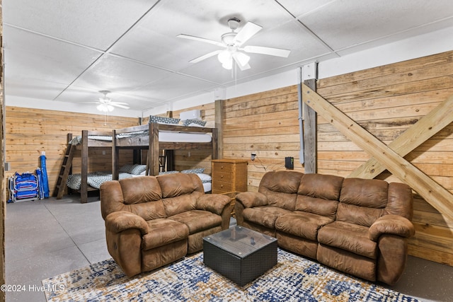 living room featuring ceiling fan and wooden walls