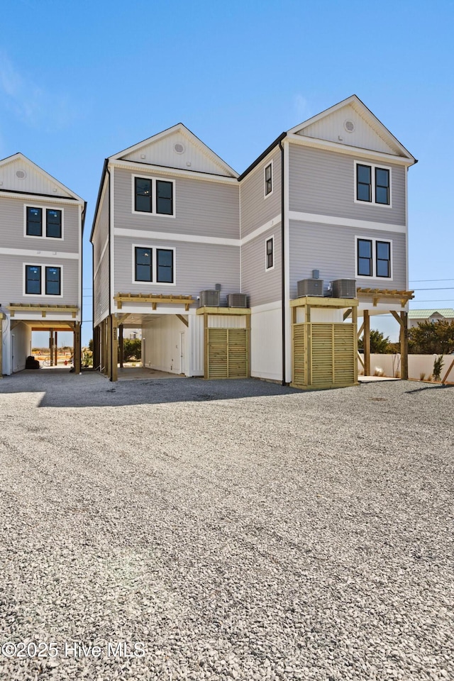 coastal inspired home with a carport, gravel driveway, and central air condition unit