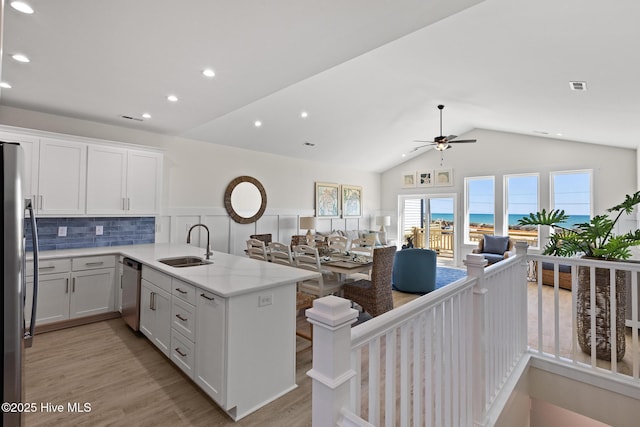 kitchen featuring a peninsula, appliances with stainless steel finishes, open floor plan, and a sink