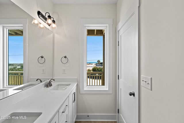 full bath with a sink, baseboards, and double vanity