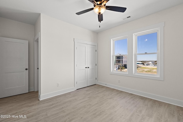 unfurnished bedroom with ceiling fan, light wood-style flooring, visible vents, baseboards, and a closet