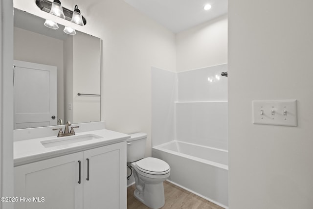 bathroom featuring toilet, tub / shower combination, wood finished floors, and vanity