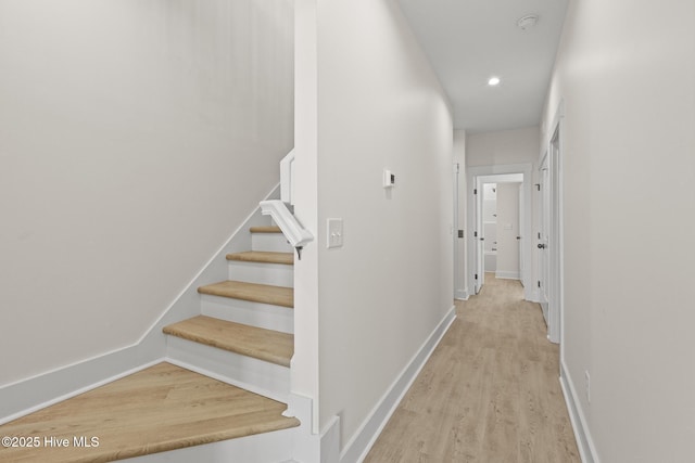 hallway with stairs, recessed lighting, light wood-type flooring, and baseboards