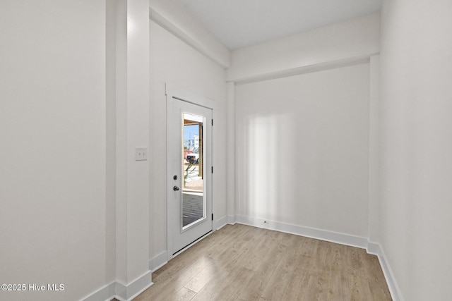 doorway featuring light wood finished floors and baseboards