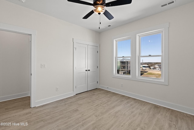 unfurnished bedroom with light wood-style flooring, visible vents, and baseboards