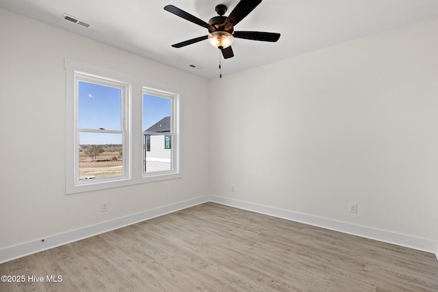 spare room featuring light wood-type flooring, baseboards, visible vents, and a ceiling fan