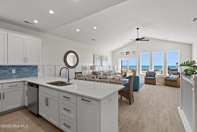 kitchen featuring a peninsula, a sink, visible vents, open floor plan, and stainless steel dishwasher