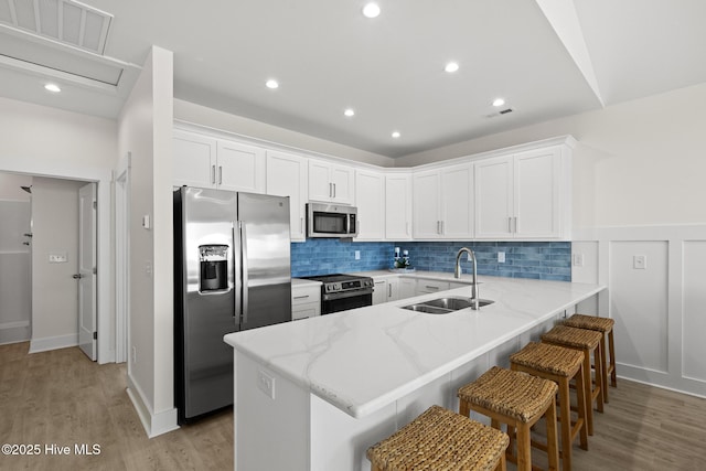 kitchen with visible vents, appliances with stainless steel finishes, white cabinets, a sink, and a peninsula