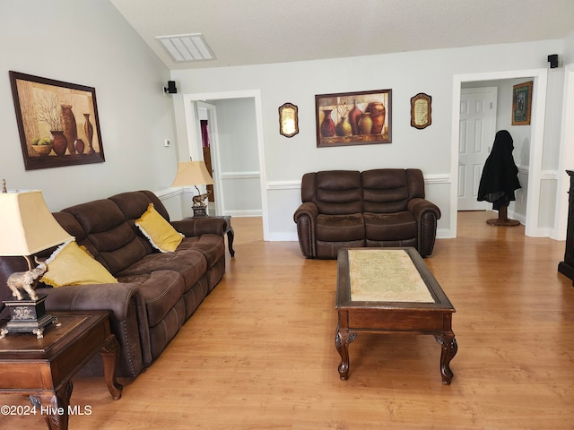 living room with light hardwood / wood-style floors and vaulted ceiling