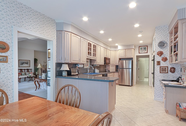 kitchen with sink, kitchen peninsula, stainless steel fridge, crown molding, and light tile patterned floors