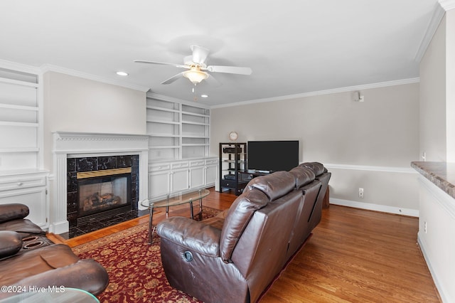 living room with hardwood / wood-style floors, ceiling fan, crown molding, built in features, and a high end fireplace