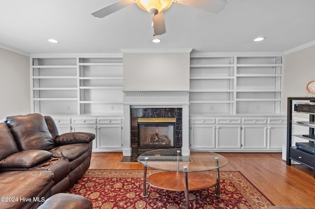 living room with ornamental molding, a premium fireplace, light hardwood / wood-style floors, and built in shelves